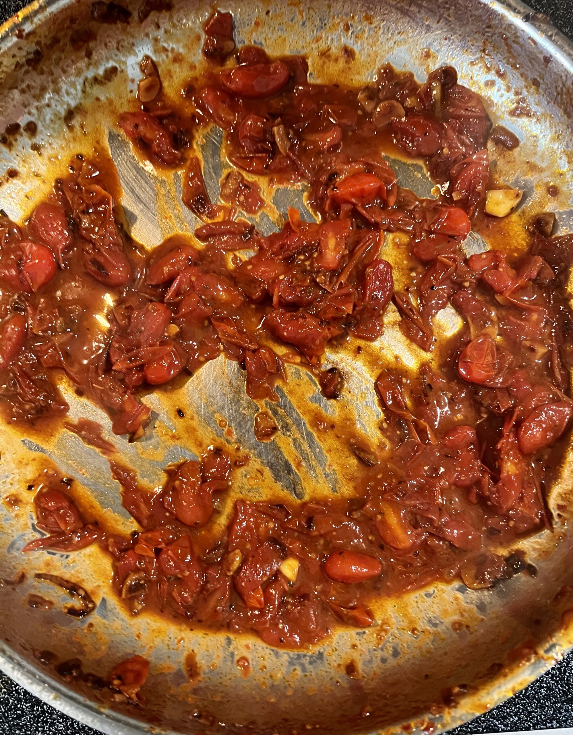 Tomatoes after a ladle of starchy pasta water is added ready for some fresh basil and rigatoni.